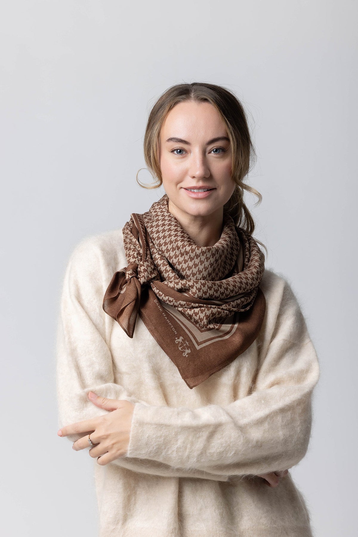 “The Dennison – Dark Hampton scarf in brown and tan houndstooth, styled as a wrap. Modal and cashmere blend with a soft, lightweight drape.”